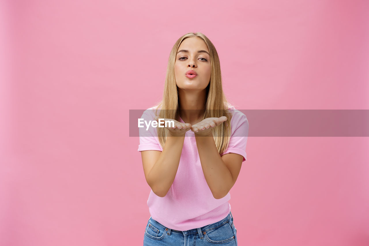 PORTRAIT OF BEAUTIFUL YOUNG WOMAN AGAINST PINK BACKGROUND