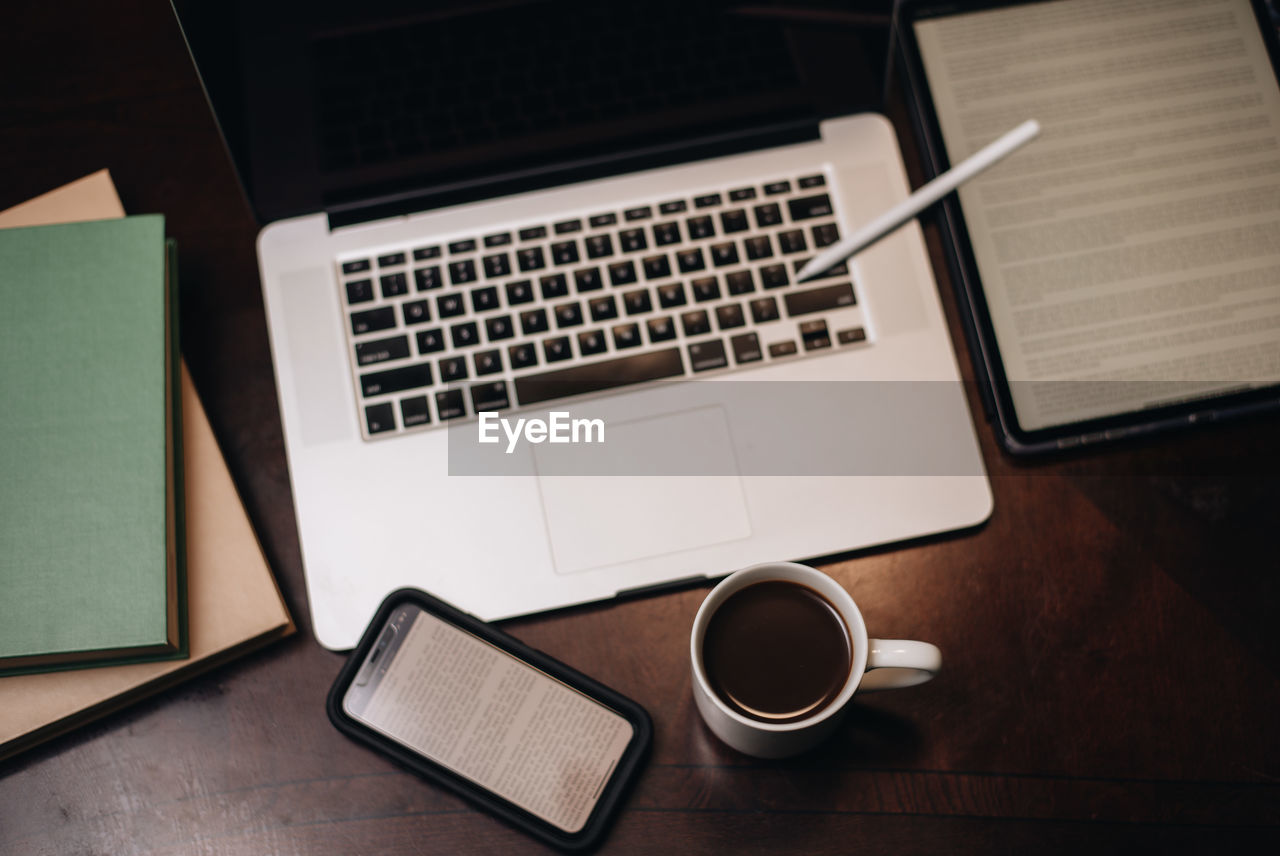 Black man drinking coffee at working at a computer desk with smartphone and laptop 