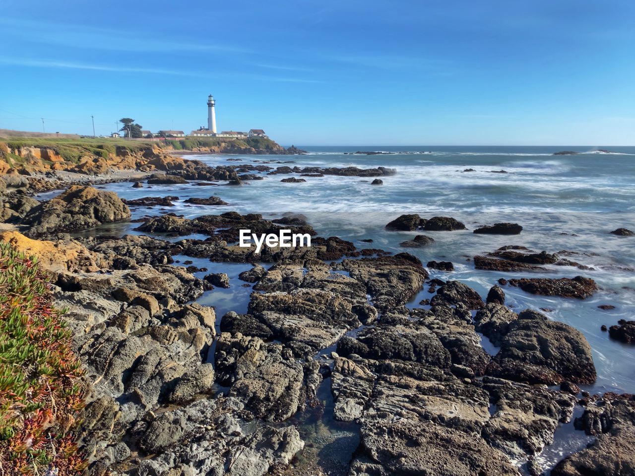 Pigeon point lighthouse landscape from pigeon point bluffs, blue sky, rocky coastline foreground