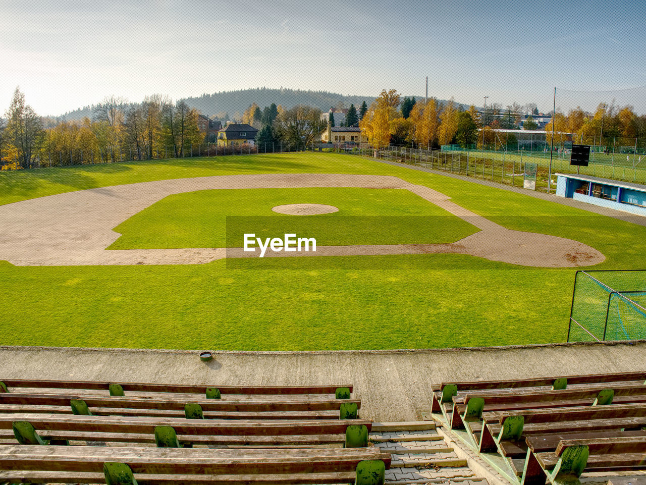 Youth baseball field viewed from behind home net in morning light.