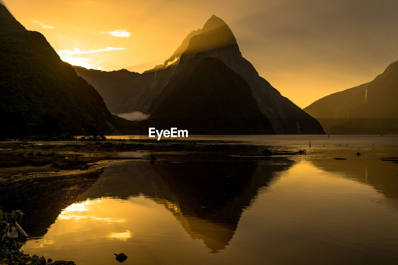 Scenic view of lake against mountains at sunset