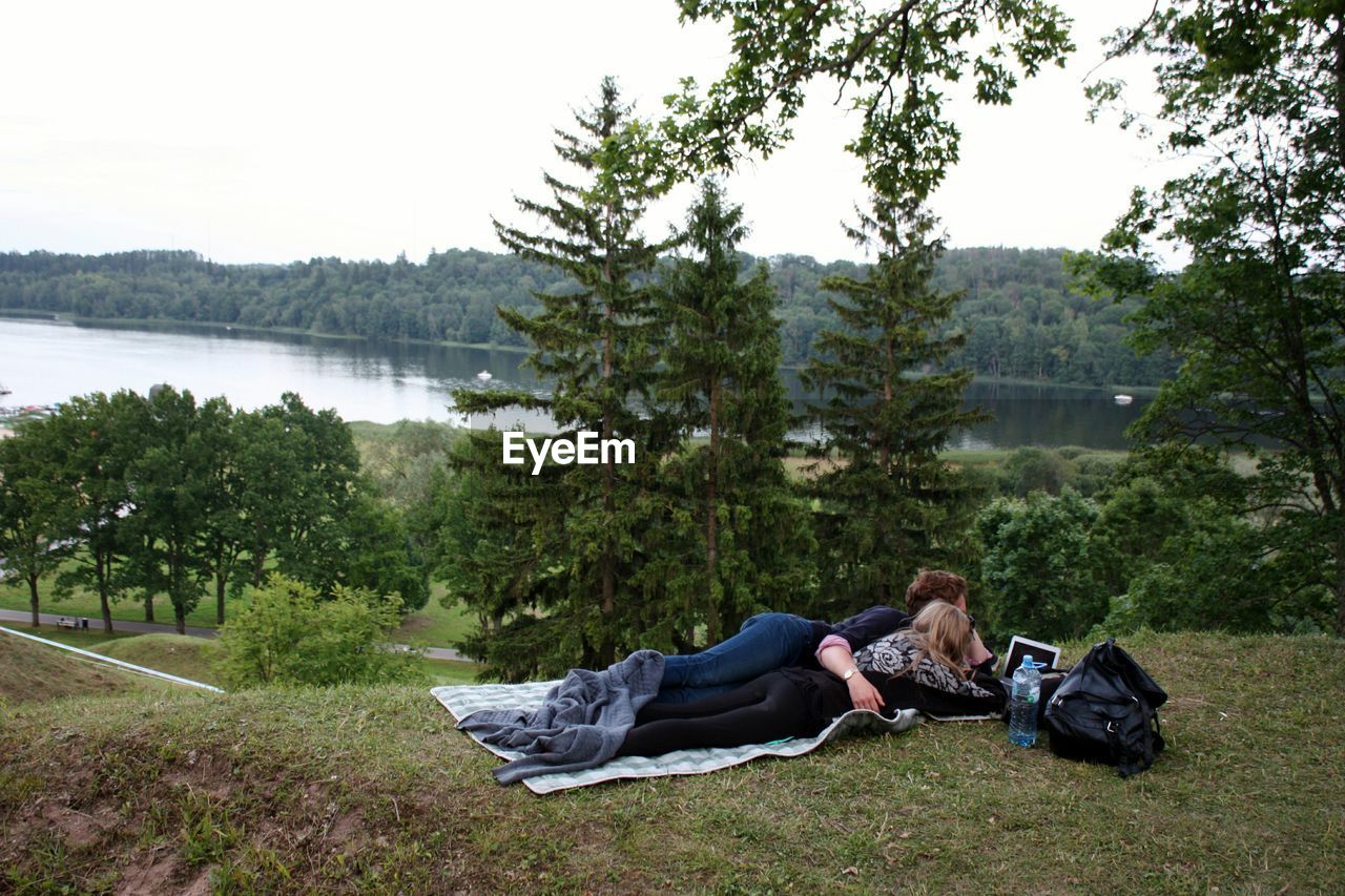 Couple relaxing on hill by trees