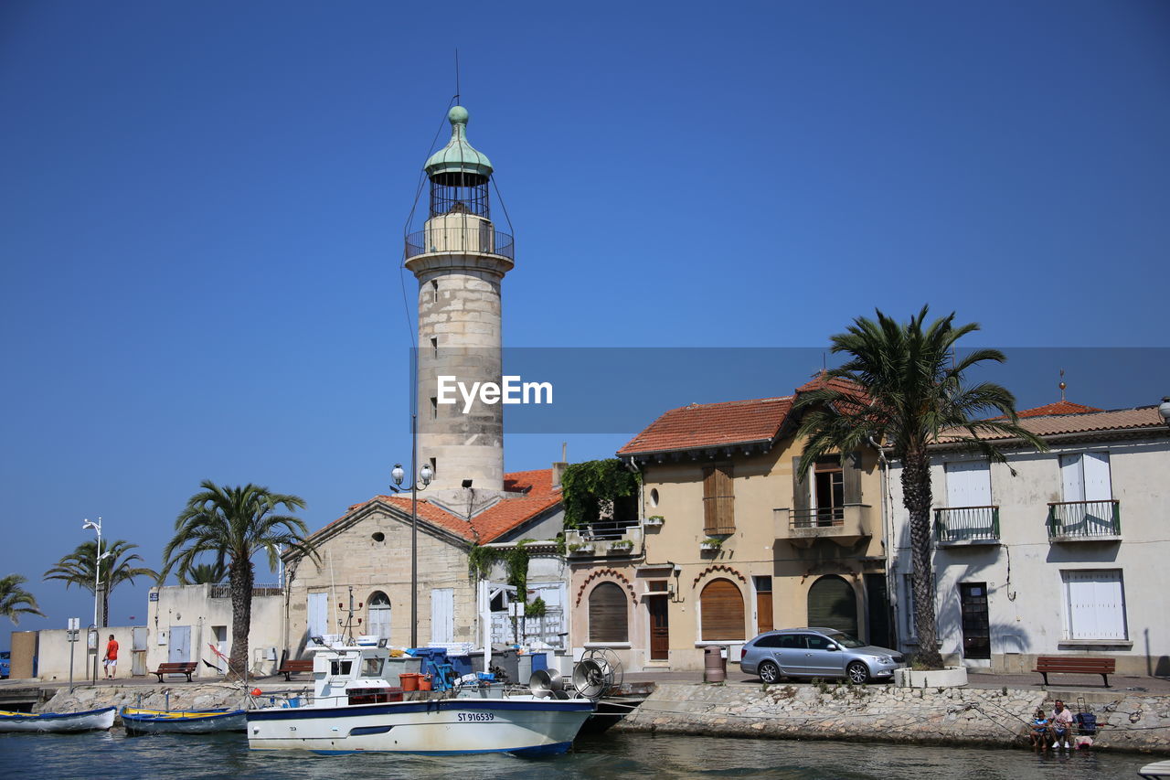 Lighthouse by sea against clear sky