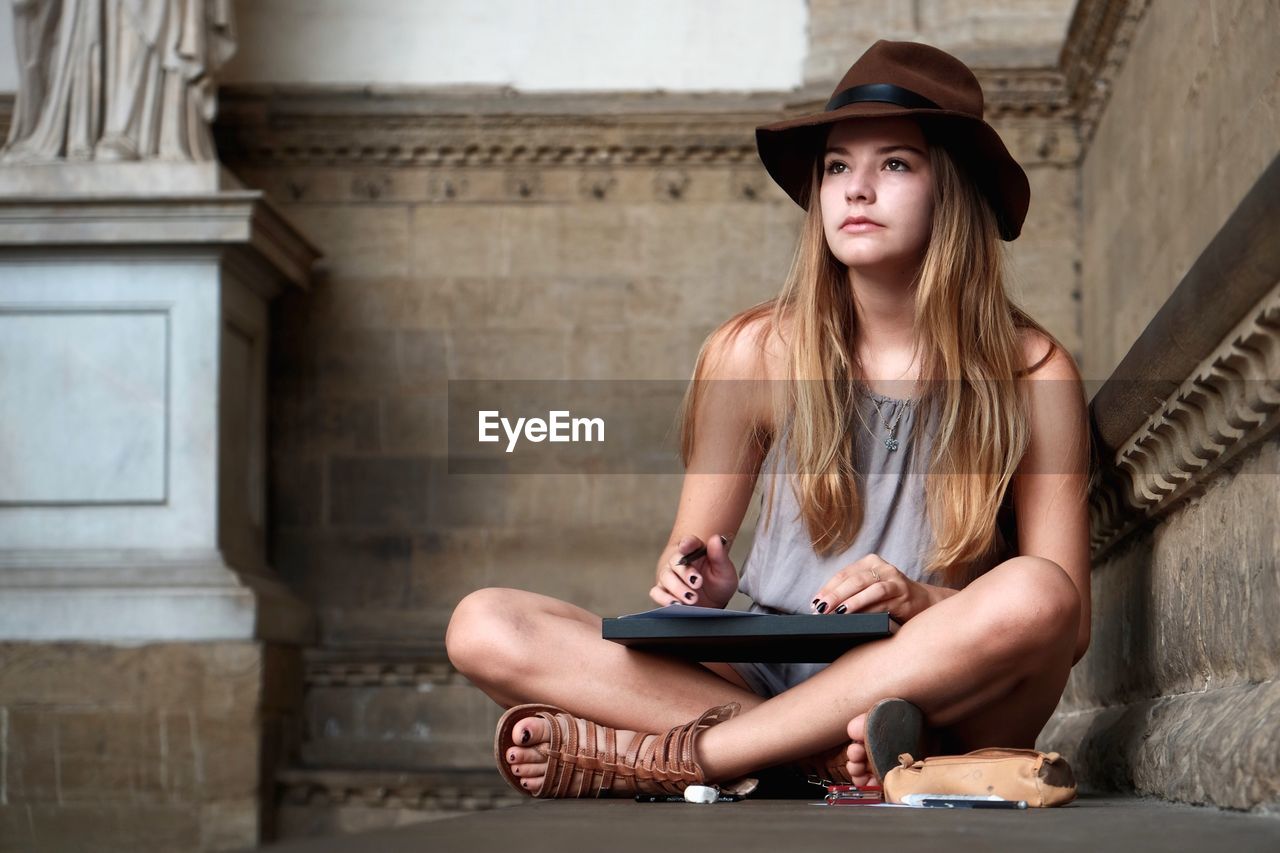 Young woman wearing hat sitting in building