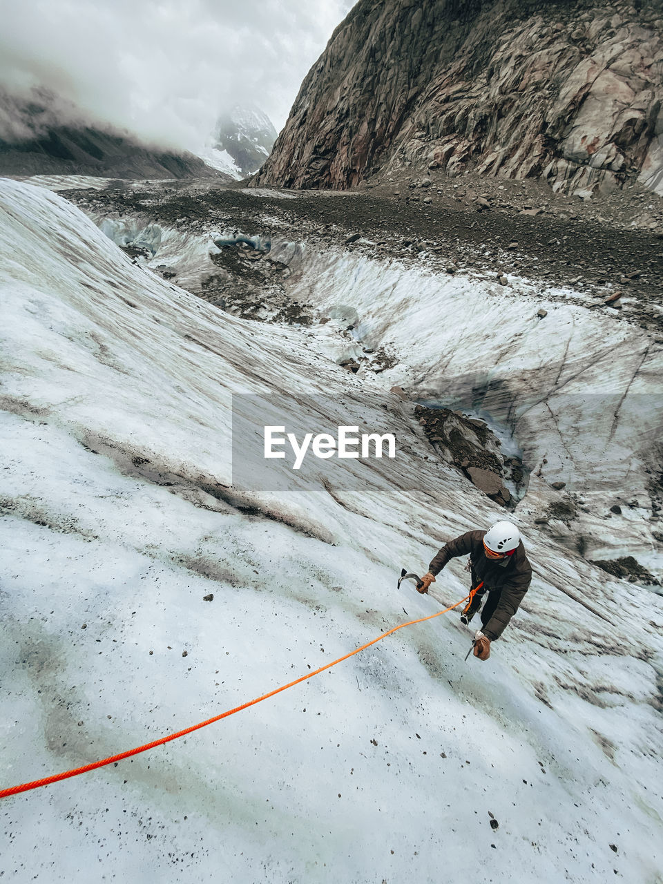 High angle shot of man climbing a steep ice face with ice axes