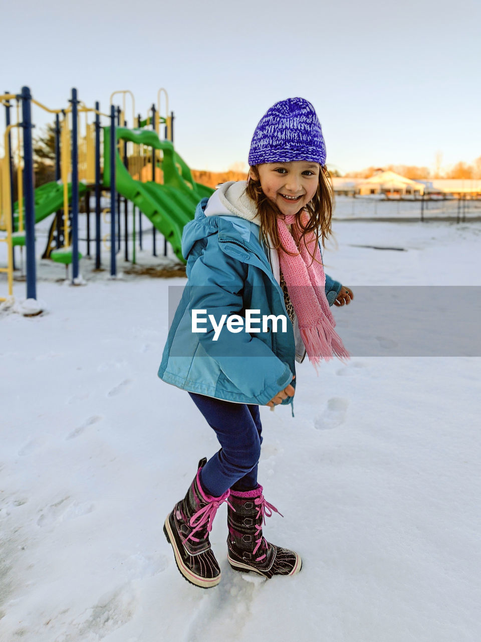 Portrait of happy girl playing on snow covered land