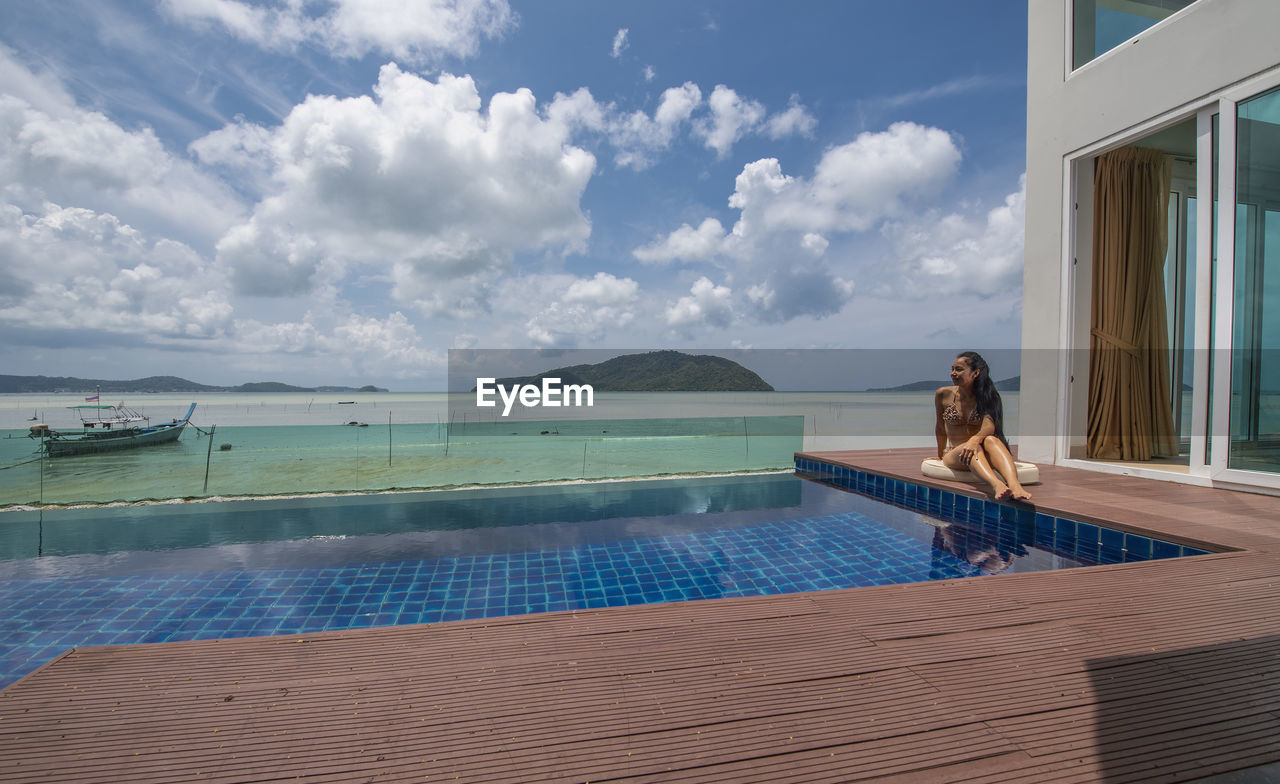 Beautiful woman sitting by the pool at luxury villa in phuket