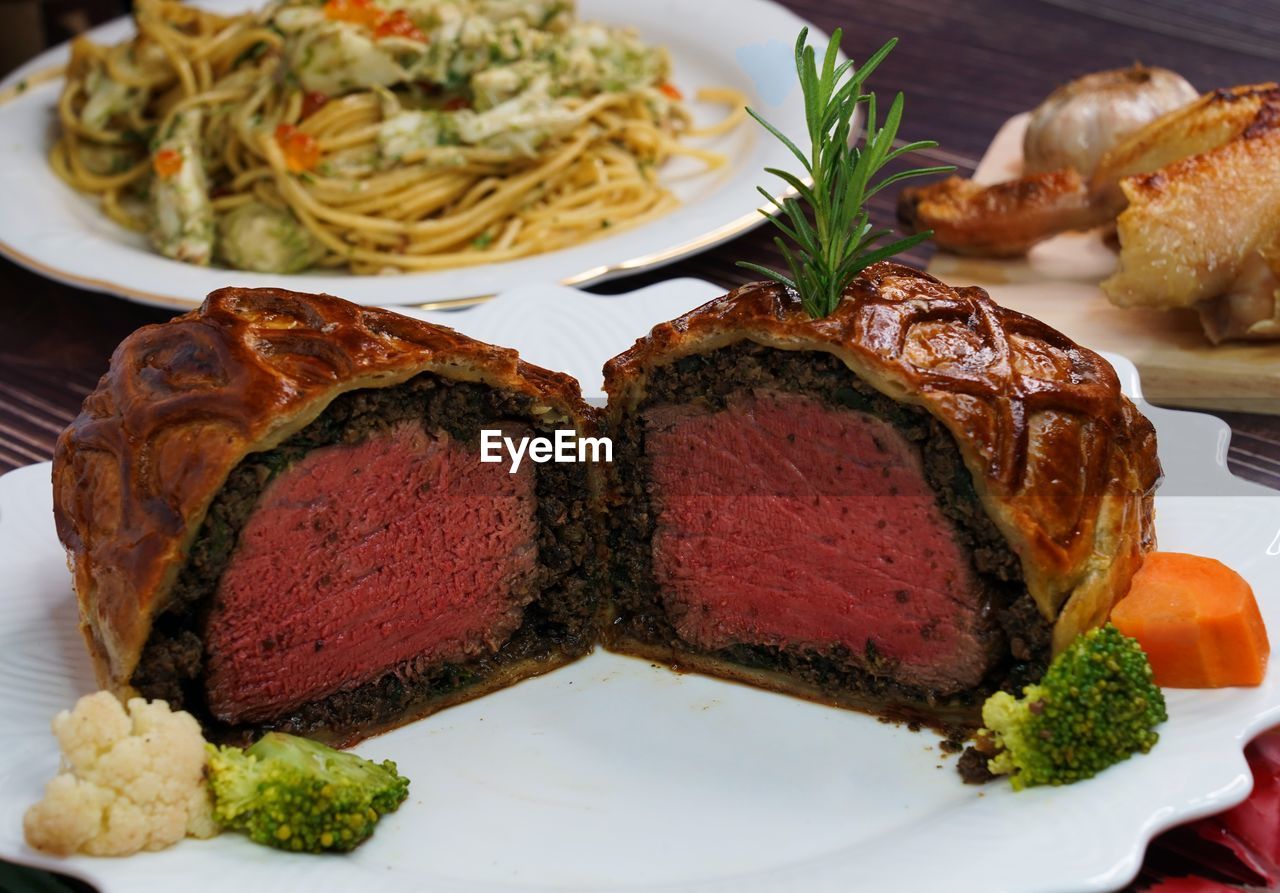 High angle beef wellington cooking cut into slices on the white plate.