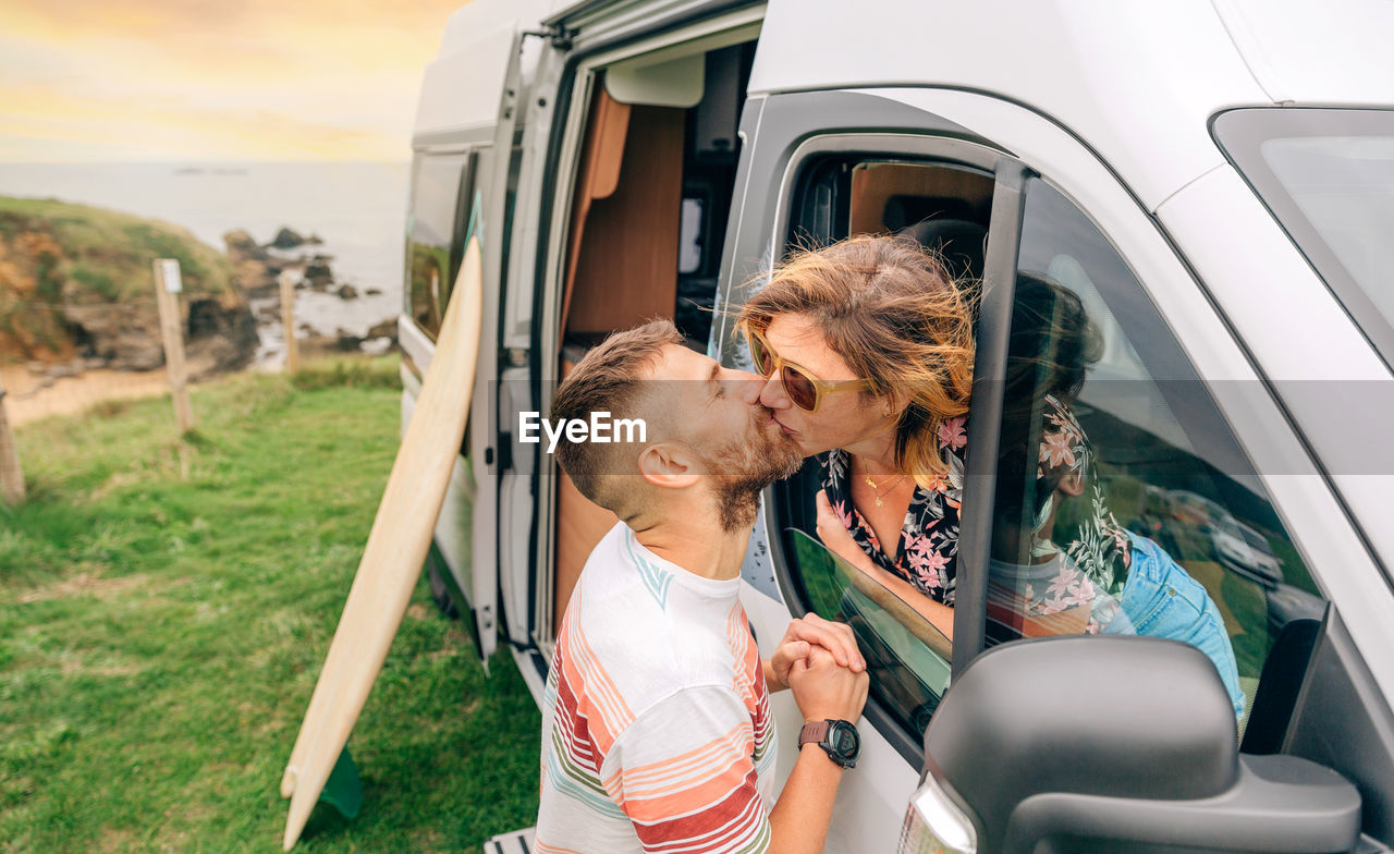 Couple kissing through the camper van window during a trip