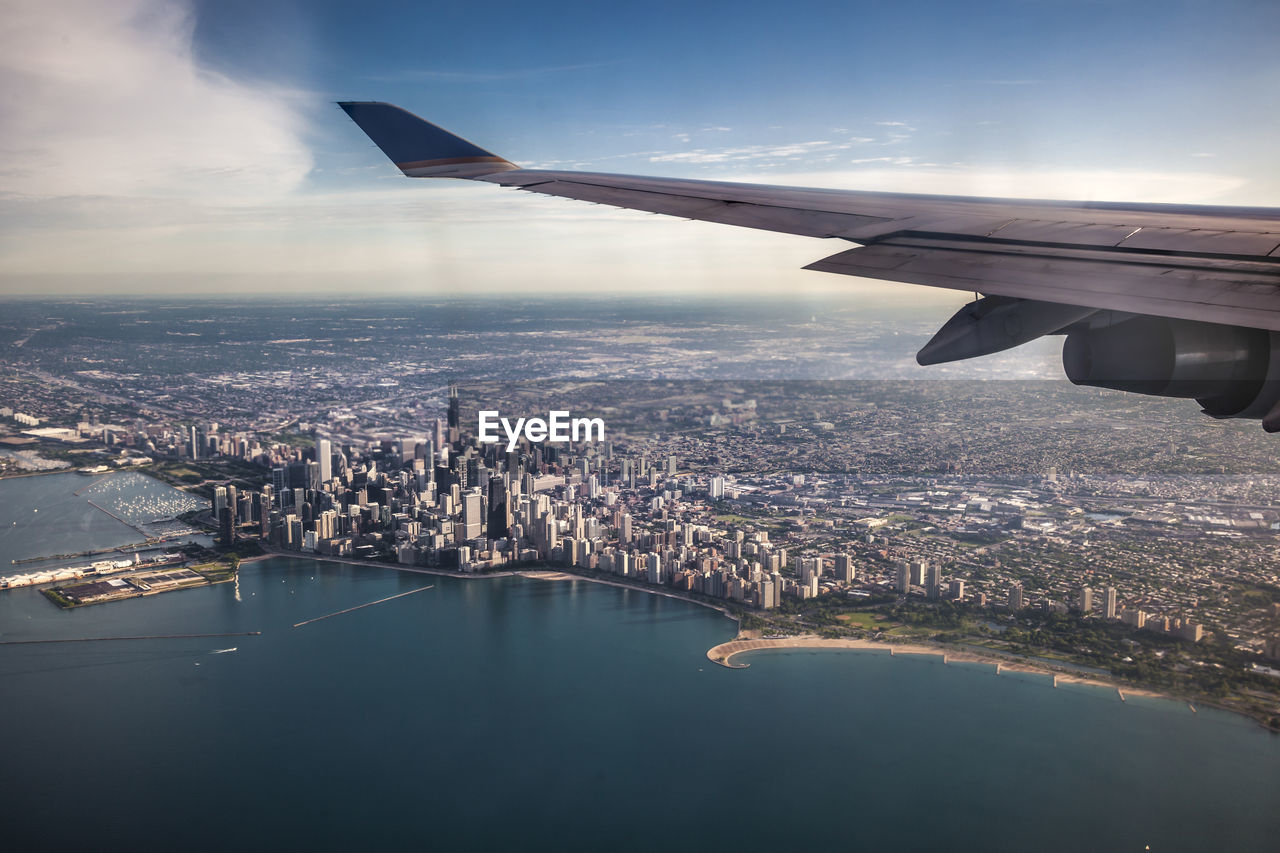 Cropped image of airplane wing flying over lake