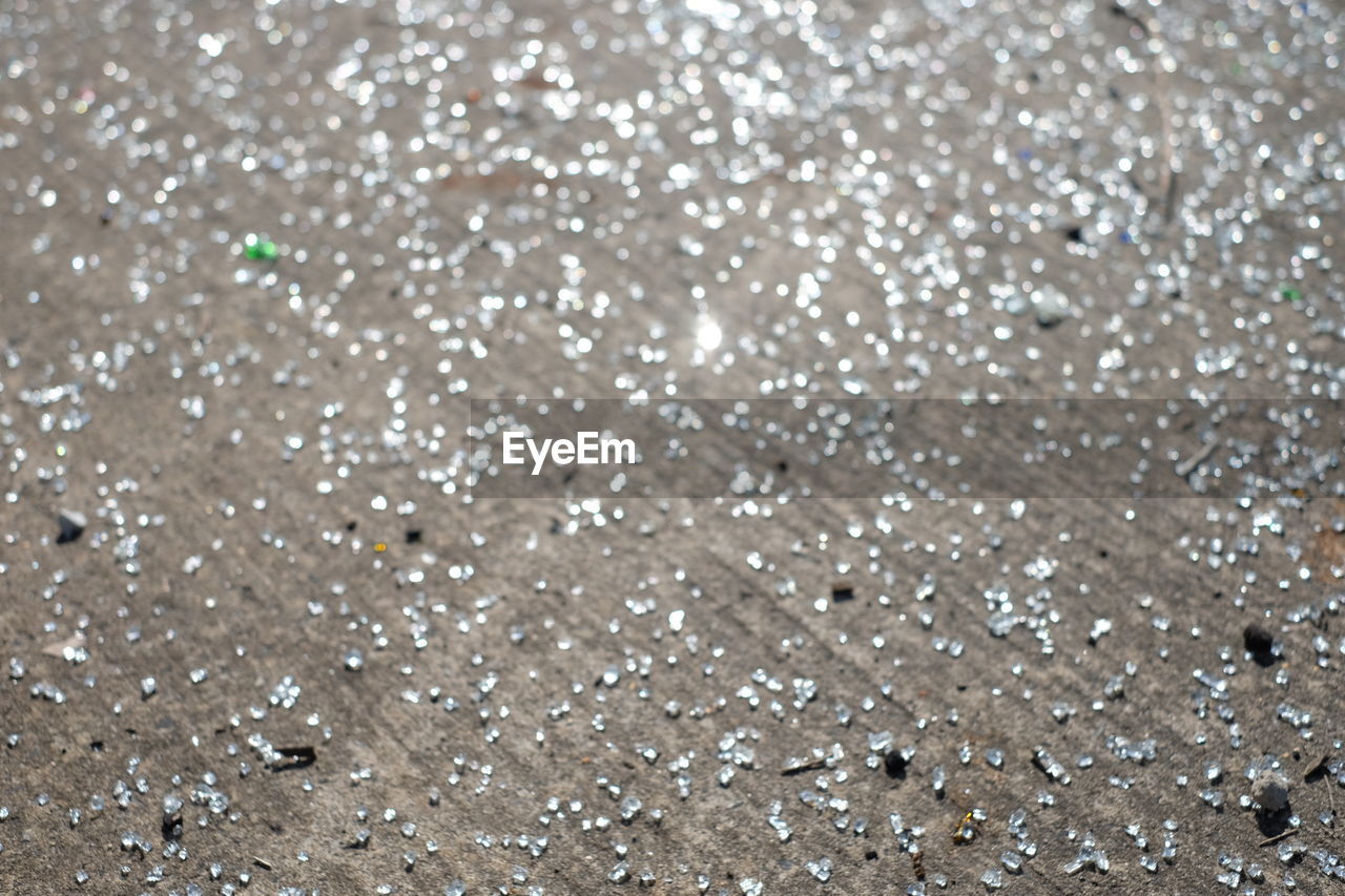 High angle view of shattered glass on concrete footpath