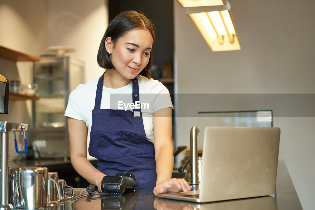 portrait of young woman using mobile phone while sitting at table