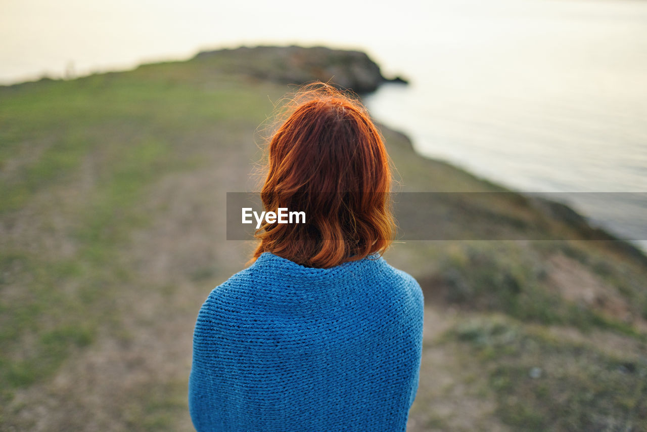 REAR VIEW OF WOMAN LOOKING AT WATERFALL