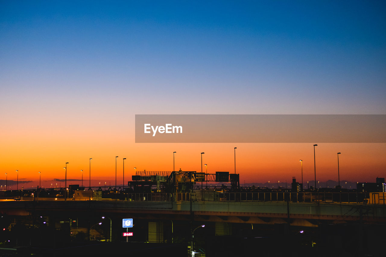 ILLUMINATED CITY AGAINST SKY AT DUSK