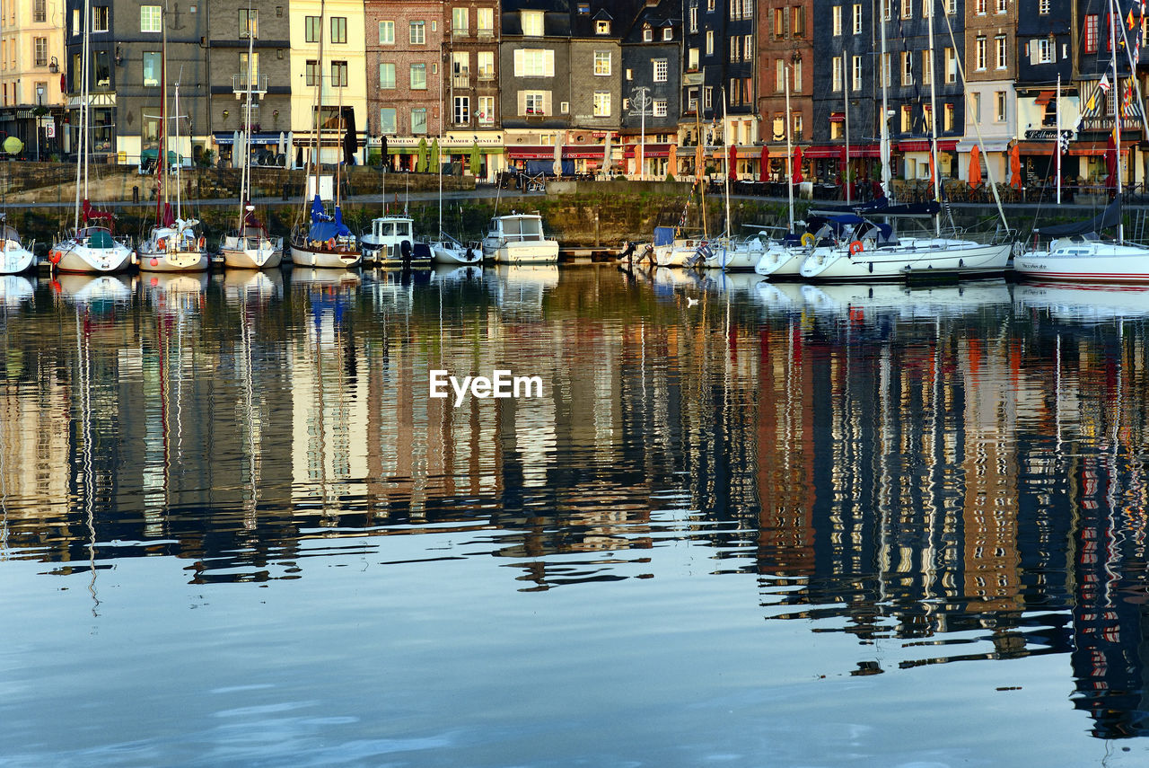 Boats moored in lake against buildings in city