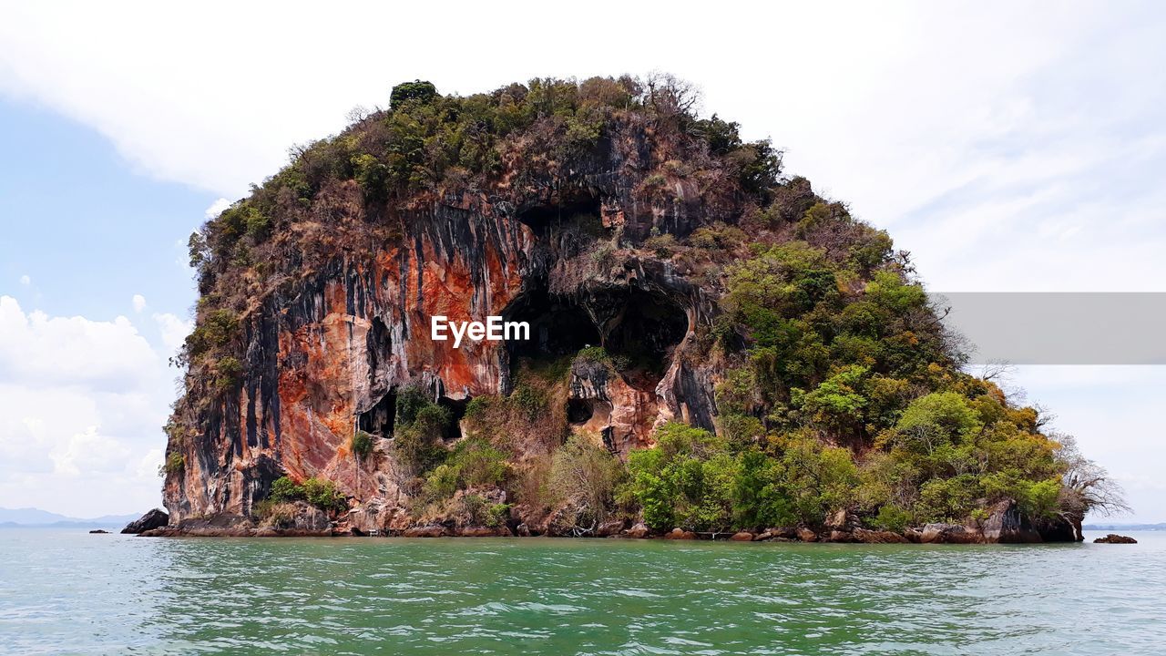 ROCK FORMATION AMIDST SEA AGAINST SKY