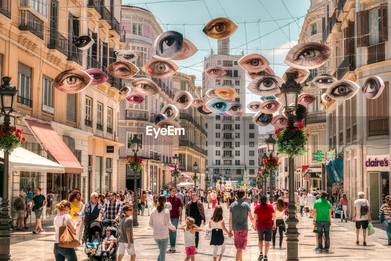 PEOPLE WALKING ON STREET AGAINST BUILDINGS