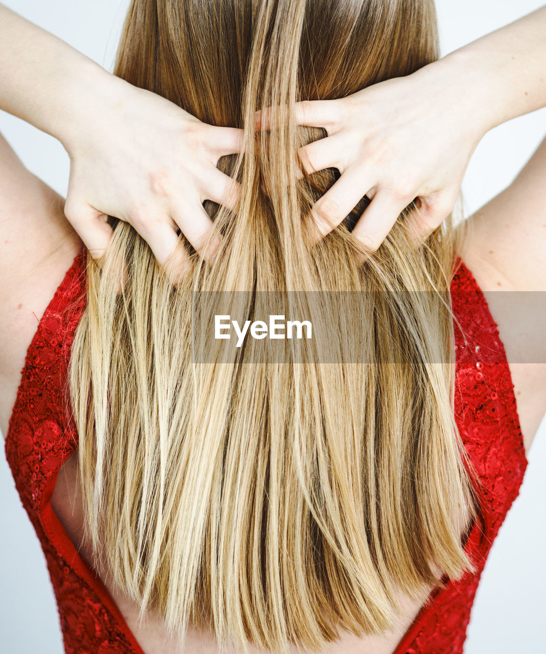 Rear view of woman with hands in hair against white background