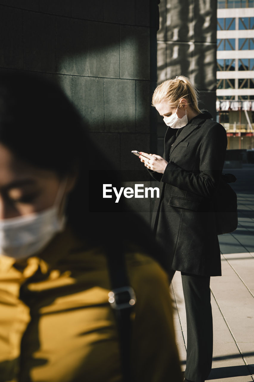 Women standing in street wearing face mask
