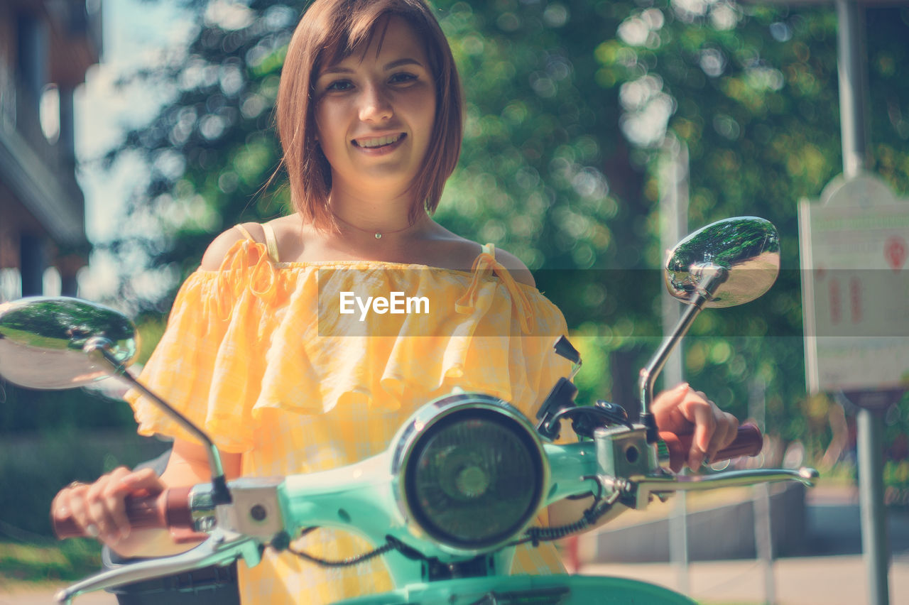 Portrait of smiling young woman sitting on motor scooter