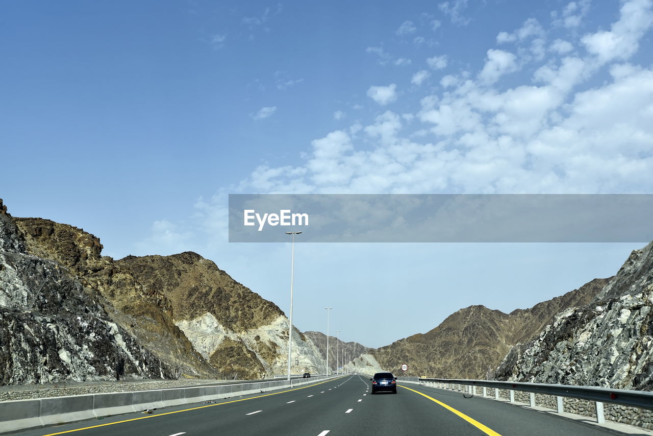 Cars on road by mountain against sky