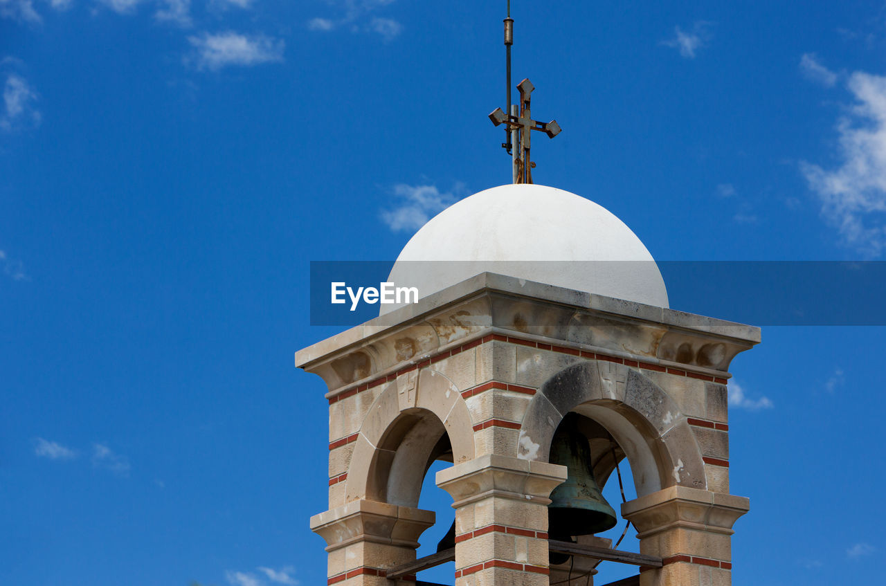 Low angle view of church bell tower against blue sky