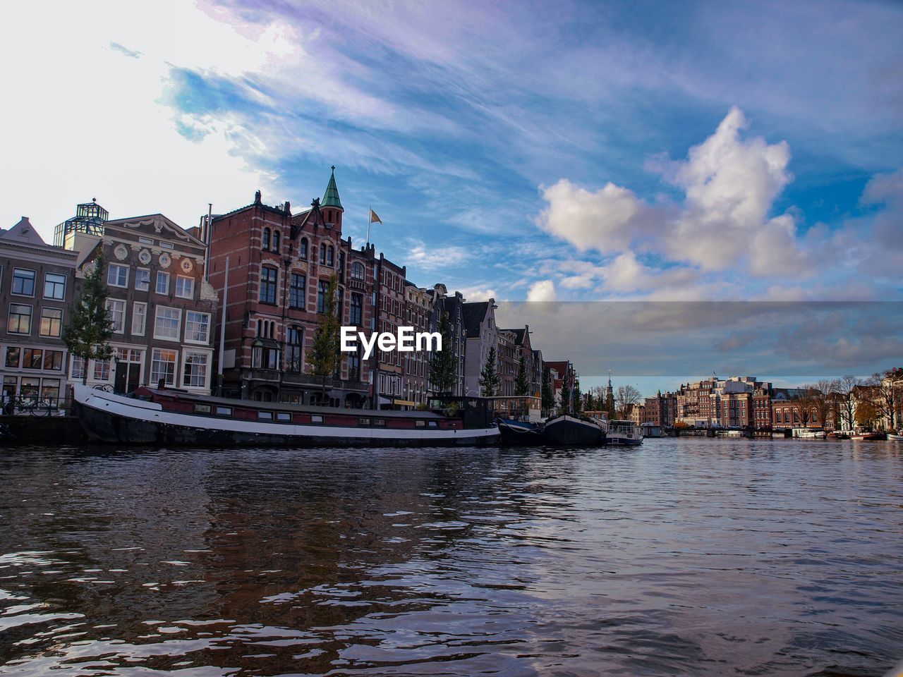 Buildings by river against sky in city