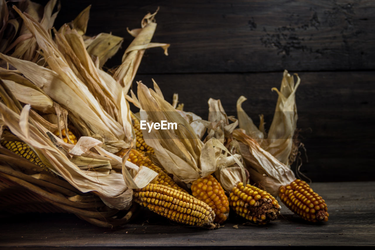 Spilled corn in a basket on dark rustic background