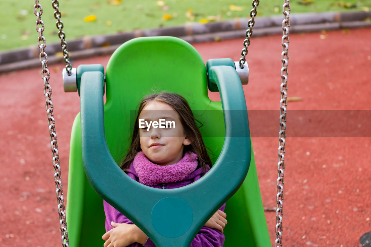 Close-up of girl on swing in playground