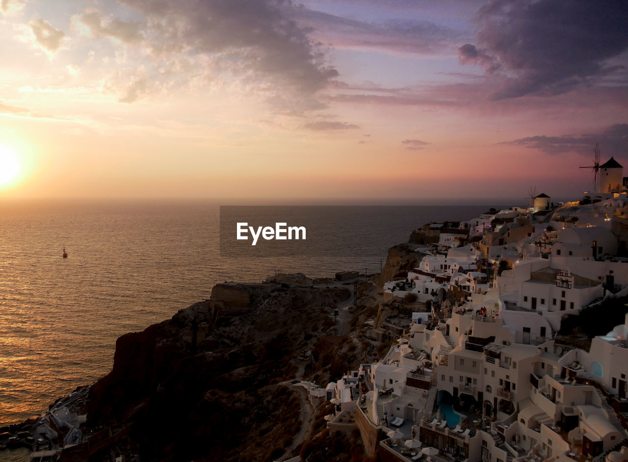 High angle view of sea and buildings against sky during sunset