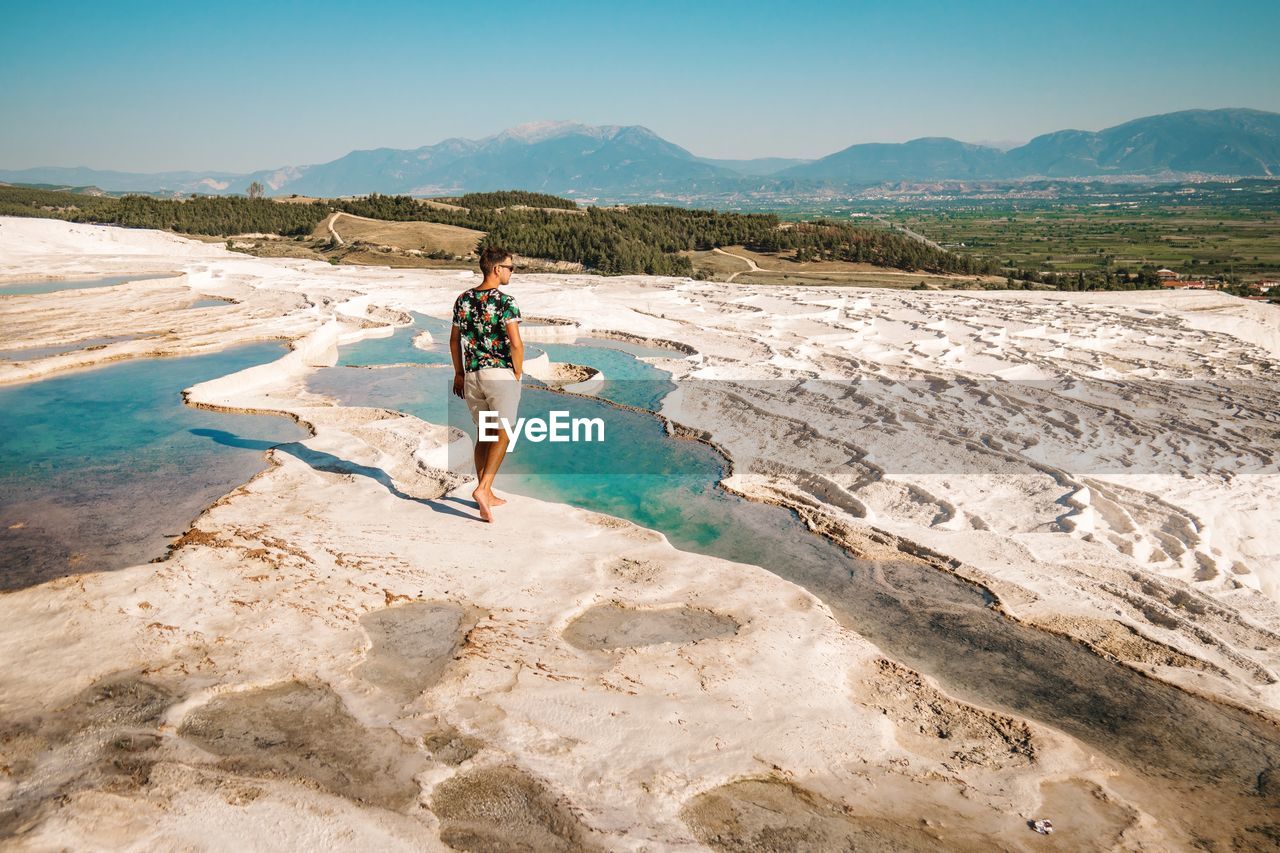 Full length of man walking at salt flat against sky