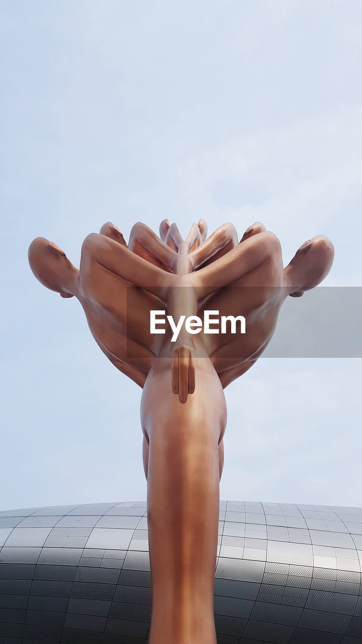 LOW ANGLE VIEW OF WOMAN HAND AGAINST BUILT STRUCTURE