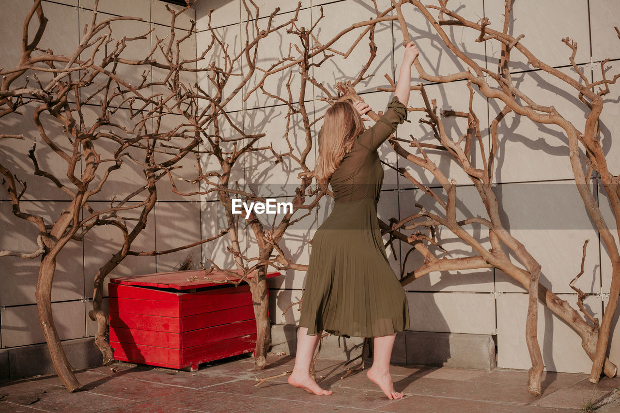 Woman standing against bare trees