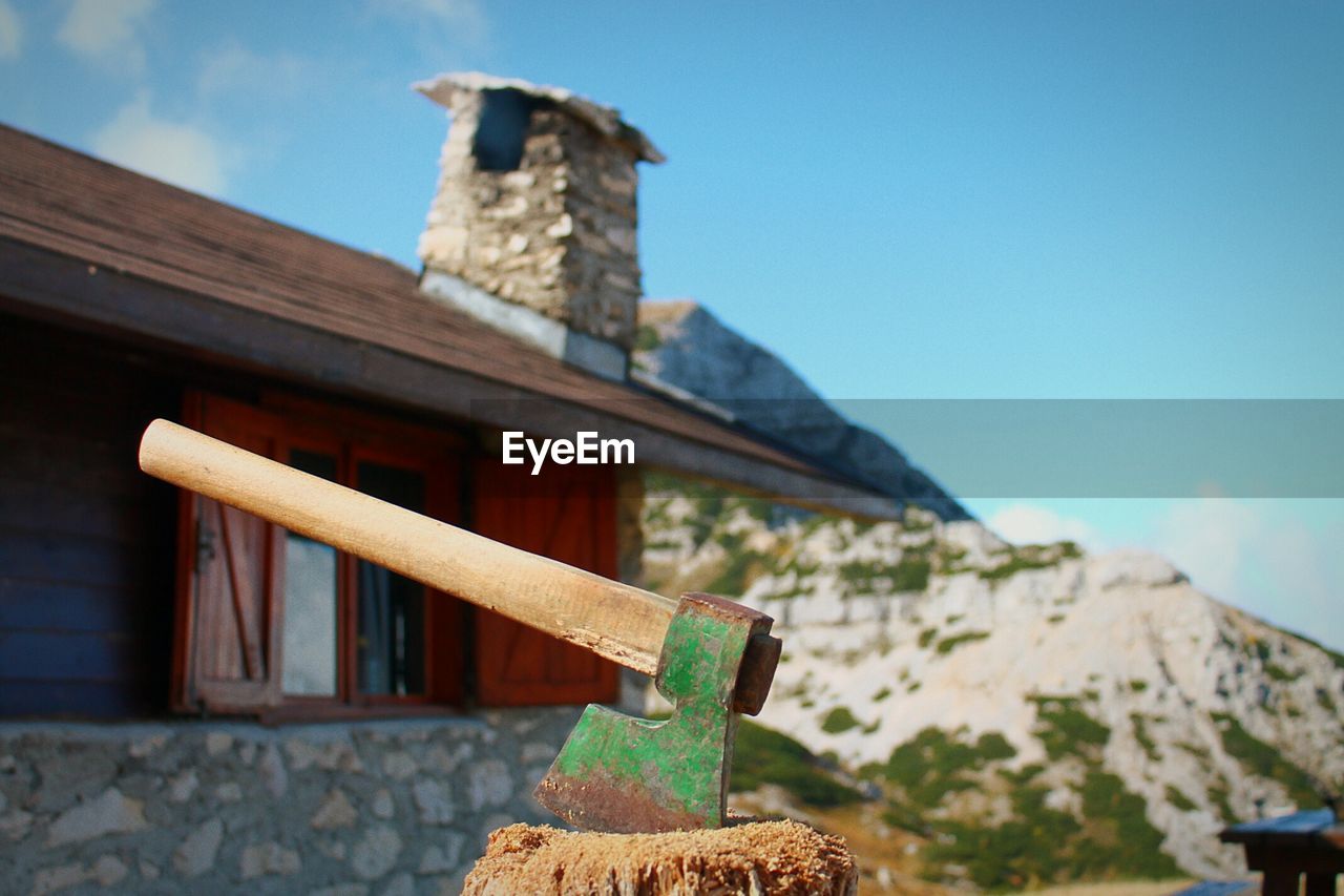 Close-up of axe on wood against sky