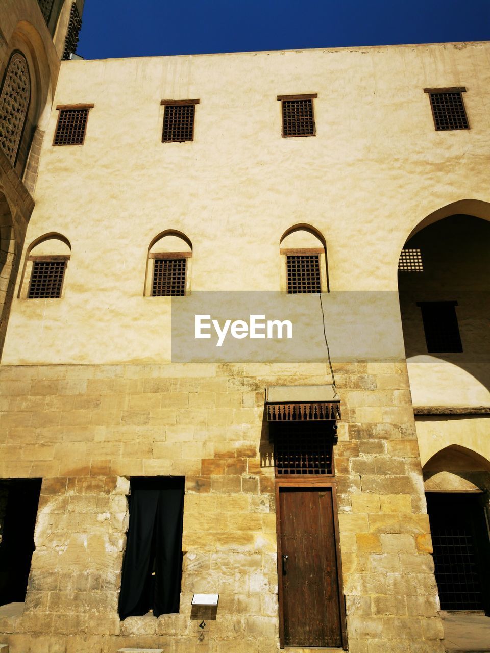 architecture, building exterior, built structure, window, building, low angle view, no people, ancient history, facade, wall, house, day, sunlight, residential district, history, outdoors, nature, city, the past, sky, arch, old