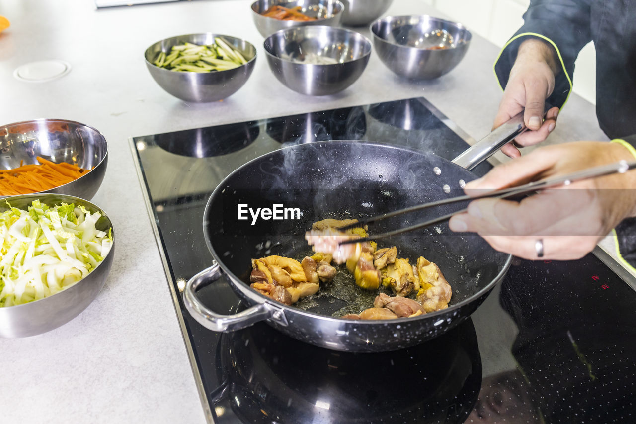 MIDSECTION OF MAN PREPARING FOOD AT KITCHEN