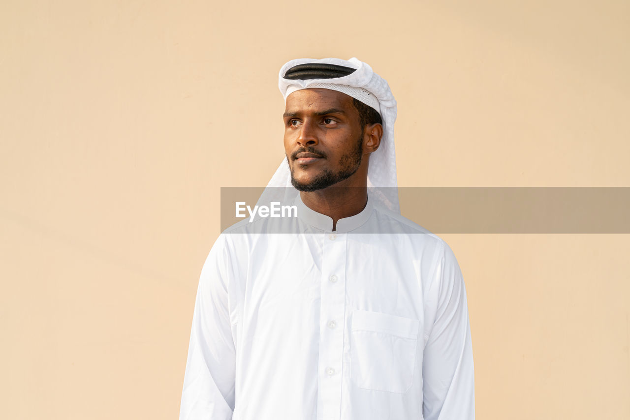 portrait of young man standing against yellow background