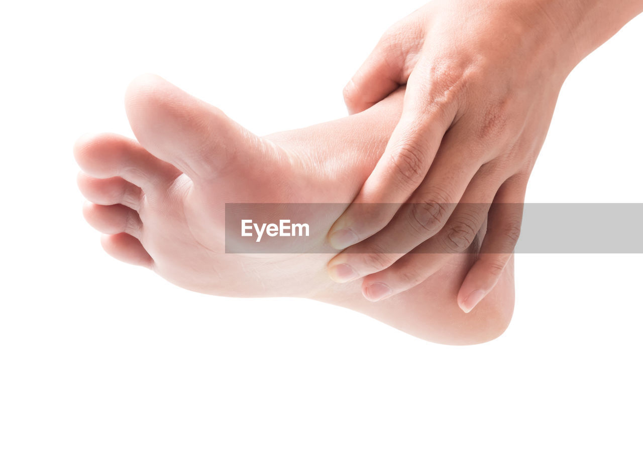 Low section of woman touching foot against white background