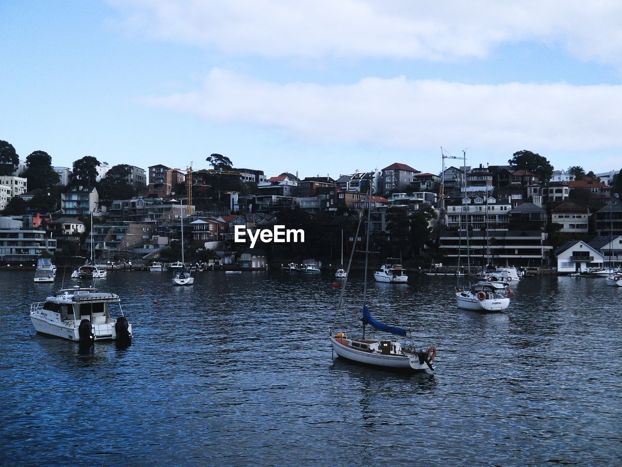 SAILBOATS MOORED ON SEA BY BUILDINGS IN CITY