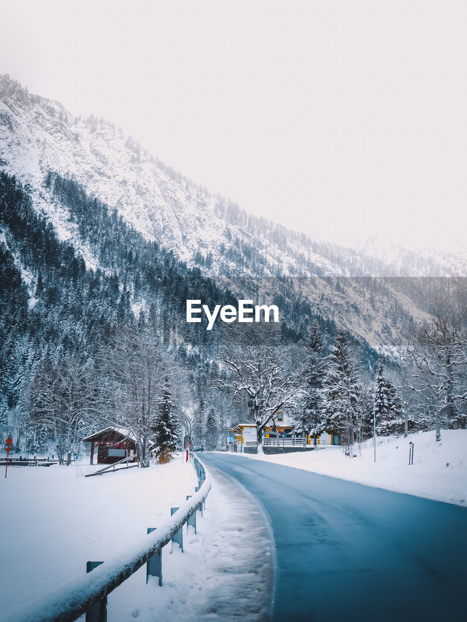 SNOW COVERED ROAD BY SNOWCAPPED MOUNTAIN AGAINST SKY