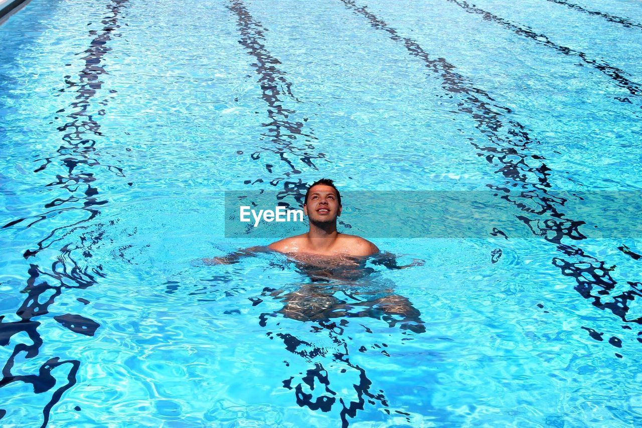 High angle view of shirtless young man swimming in pool