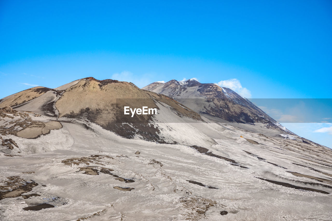 Scenic view of snowcapped mountains against blue sky