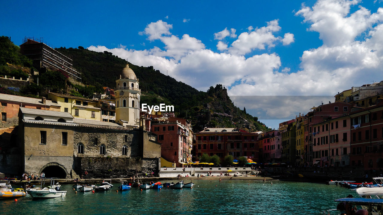 Buildings by river against sky in city