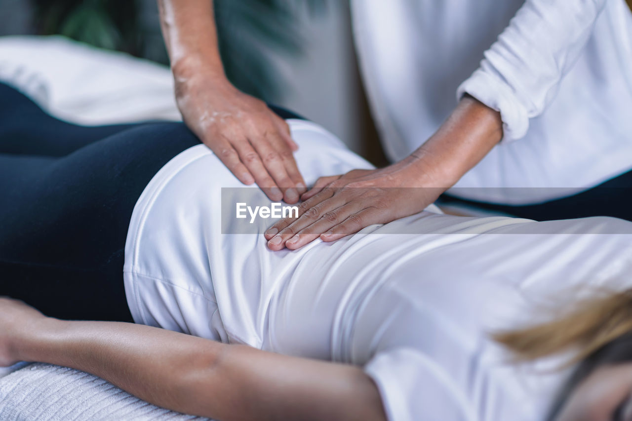 Cropped hands of therapist giving reiki treatment to teenage girl on face at spa