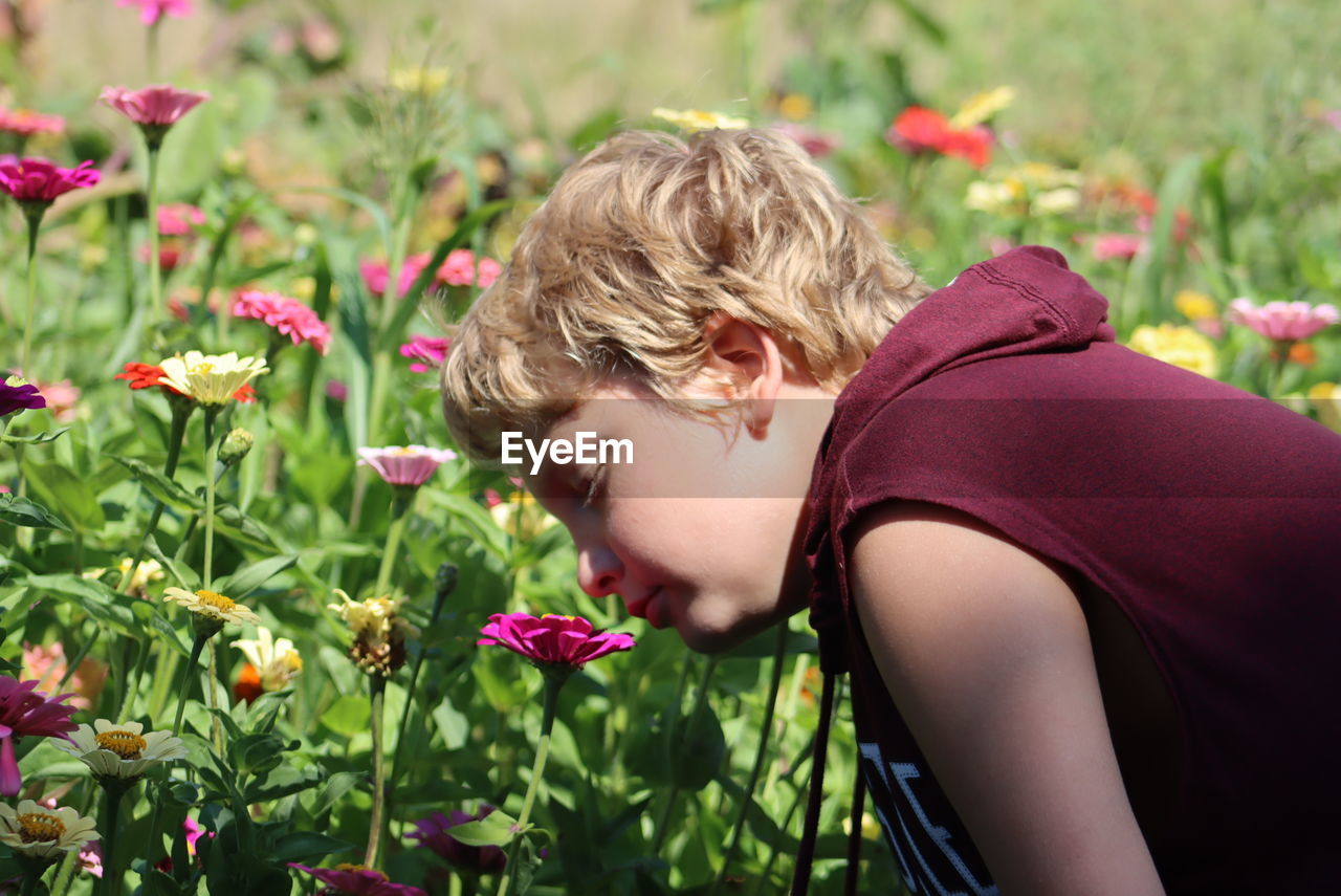 rear view of young woman picking flowers blooming outdoors