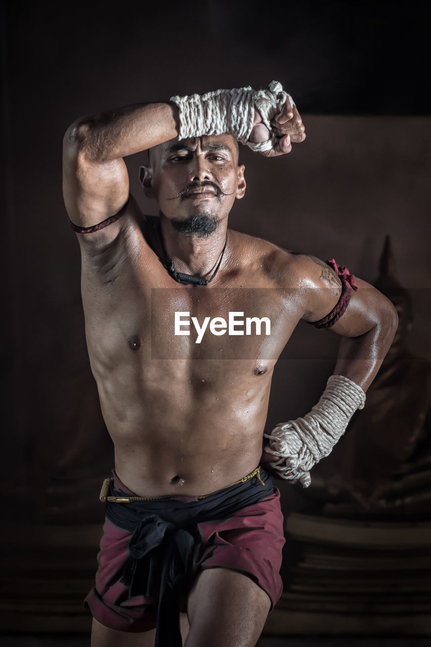 Portrait of shirtless mid adult man standing in darkroom