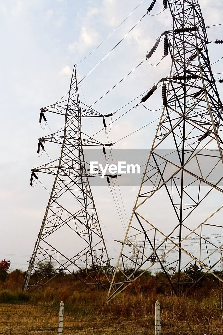 LOW ANGLE VIEW OF ELECTRICITY PYLONS ON FIELD