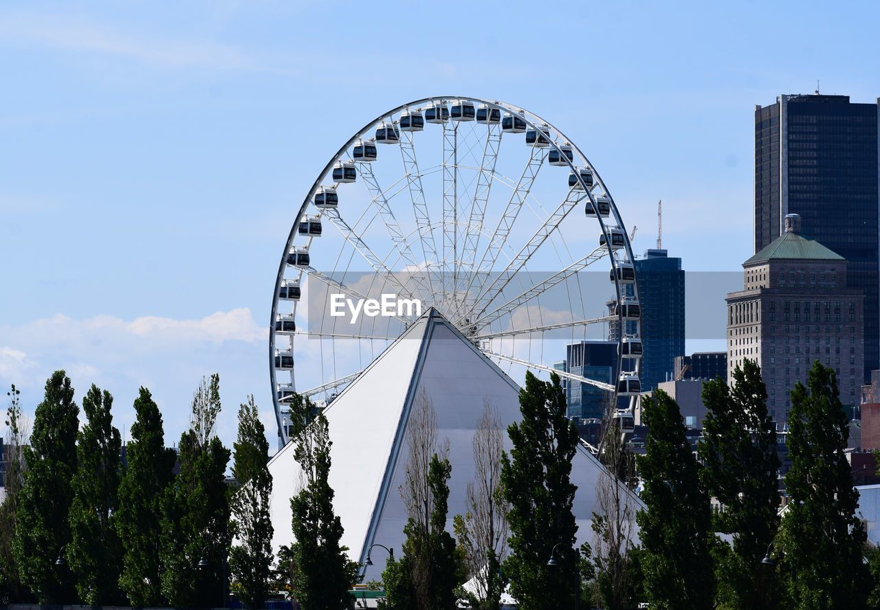 LOW ANGLE VIEW OF FERRIS WHEEL IN CITY AGAINST SKY