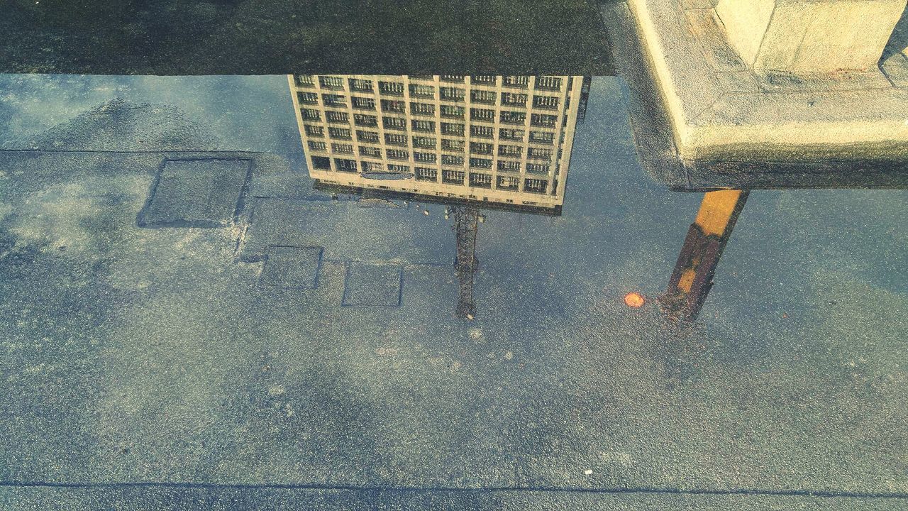 Reflection of building in water puddle