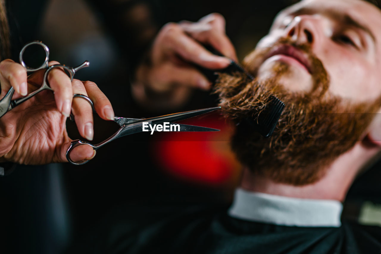 Close-up of woman cutting man beard